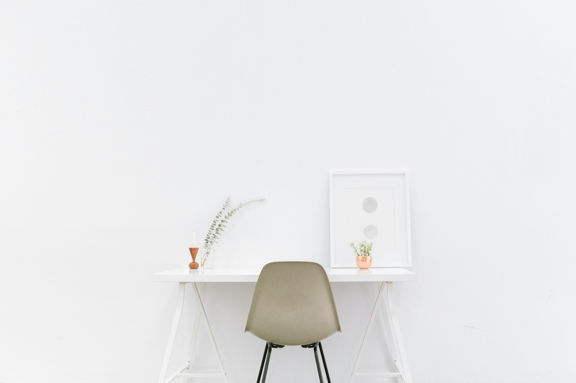 Scrivania minimale e luminosa, con una sedia e piccoli oggetti d'arredo